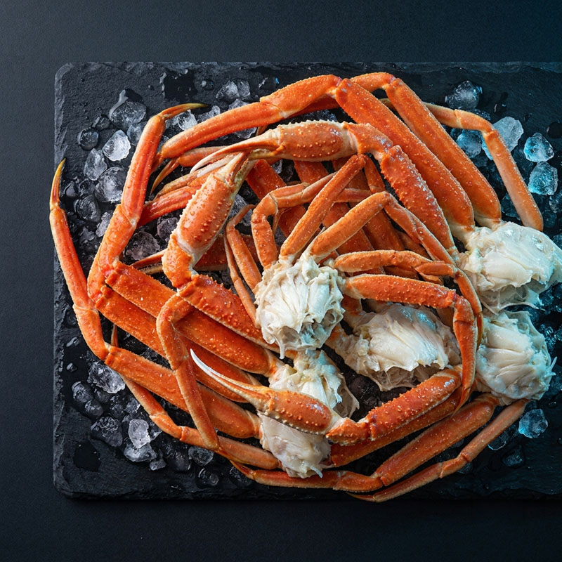 Cooked snow crab legs on a bed of ice on a dark slate platter